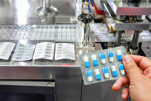 Hand holding blue capsule pack at medicine pill production line, Industrial pharmaceutical concept. Hand holding blue capsule pack at medicine pill production line, Industrial pharmaceutical concept. drug manufacturing stock pictures, royalty-free photos & images