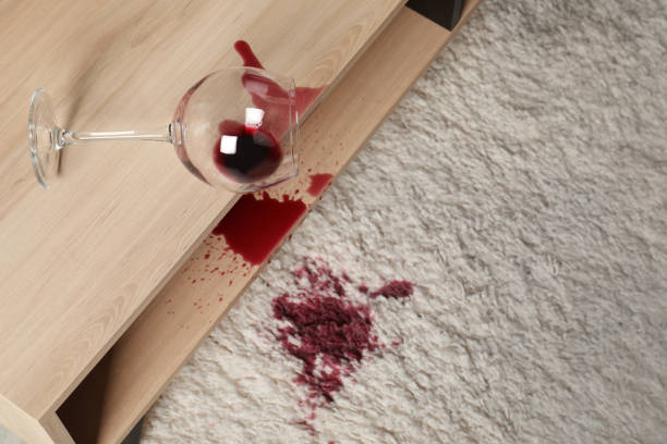 перевернутый бокал и пролитое красное вино на белый ковер в помещении, вид сверху - spilling стоковые фото и изображения