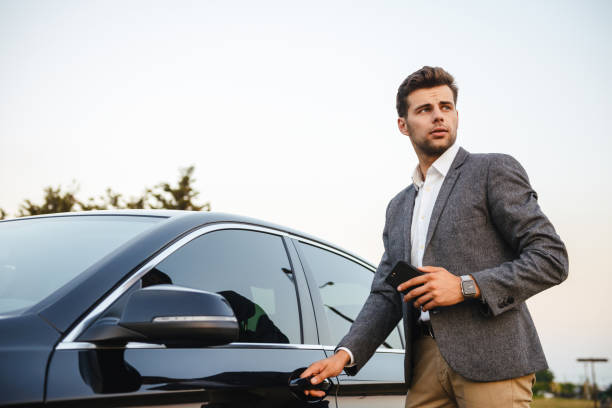 istock Confident young businessman in suit opens his car 1328308550
