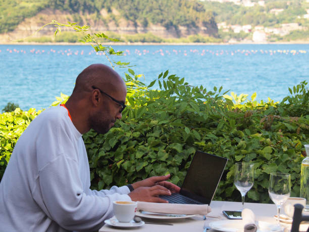 hombre trabajando con ordenador portátil en vacaciones junto al mar - alenka fotografías e imágenes de stock