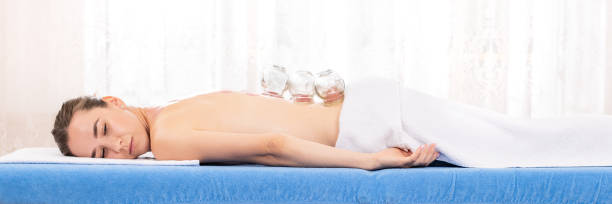 Woman Getting Cupping Treatment At a Spa. Cupping Therapy banner. Treatment used in Traditional Chinese Medicine for pain relief and other health benefits. Woman Getting Cupping Treatment At a Spa. Cupping Therapy banner. Treatment used in Traditional Chinese Medicine for pain relief and other health benefits. face down stock pictures, royalty-free photos & images