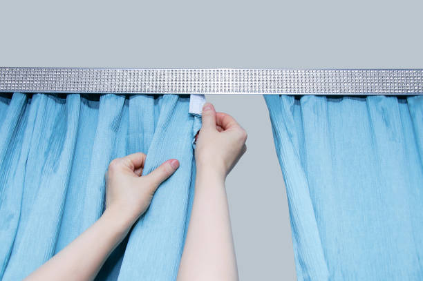istock Caucasian woman hangs blue curtains on cornice close-up. 1328316744