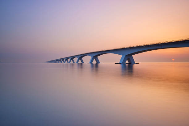 Zeelandbrug during sunrise The sun is rising from behind the Zeelandbrug. The bridge goes over a big part of water from one part of the province to the other. The water is very quiet and therefore causes reflection. dutch architecture stock pictures, royalty-free photos & images
