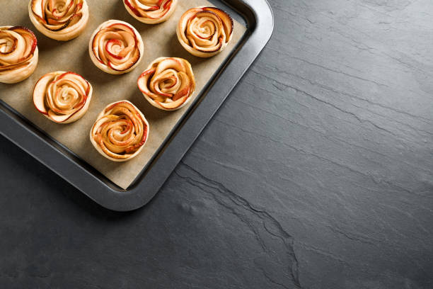bandeja con rosas de manzana recién horneadas sobre mesa negra, vista superior. espacio para texto - tart dessert tray bakery fotografías e imágenes de stock