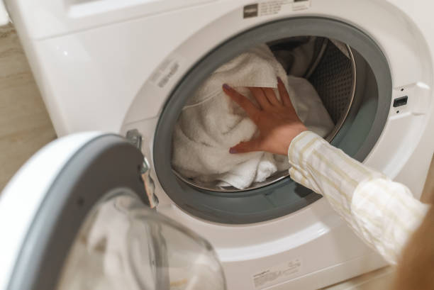 istock Teenage girl loading clothes into washing machine. 1328319680