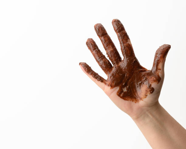 female hand soiled in melted black chocolate on a white background female hand soiled in melted black chocolate on a white background, dirty part of the body chocolate fingers stock pictures, royalty-free photos & images