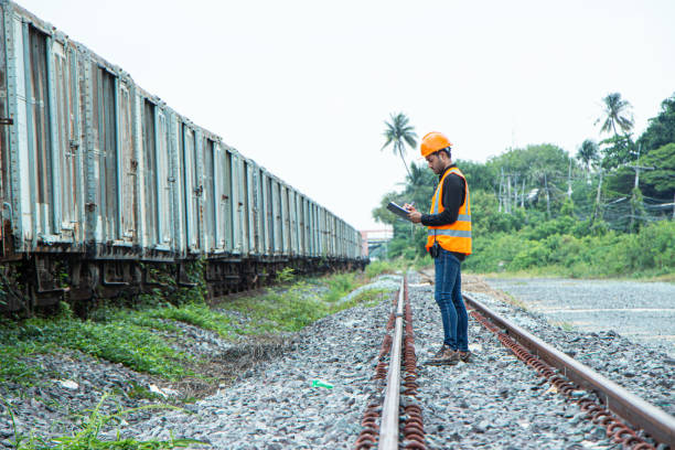 istock asian Inspector Engineering wearing helmet and vest worker unifrom checking railway construction work on rail track. 1328323544