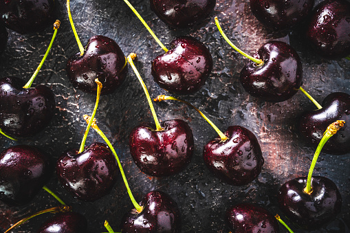 Cherry fruits fresh with dew water drops on dark gray moody background with shadows