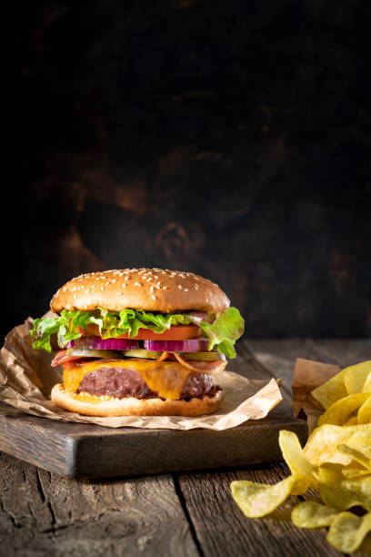 cheeseburger burger patty classico con menu patatine fritte su tavolo rustico di legno - roasted sesame seeds foto e immagini stock