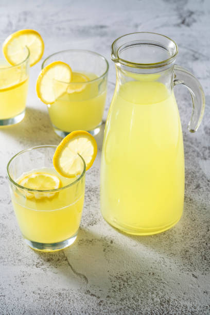 istock Lemon lemonade homemade with jar and three glasses with lemon slices on white 1328325064