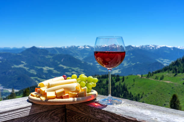 fresch tirol cheese with wine and grapes over mountain landscape fresch tirol cheese with wine and grapes over mountain landscape . swiss culture stock pictures, royalty-free photos & images