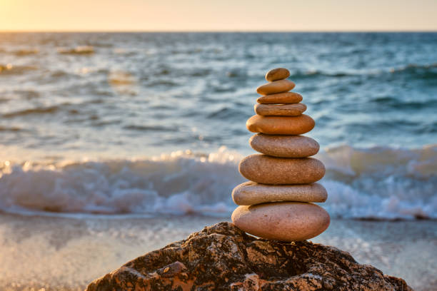 Concept of balance and harmony - stone stack on the beach Concept of balance and harmony. Cairn stack of stones pebbles cairn on the beach coast of the sea in the nature on sunset. Meditative art of stone stacking cairn stock pictures, royalty-free photos & images