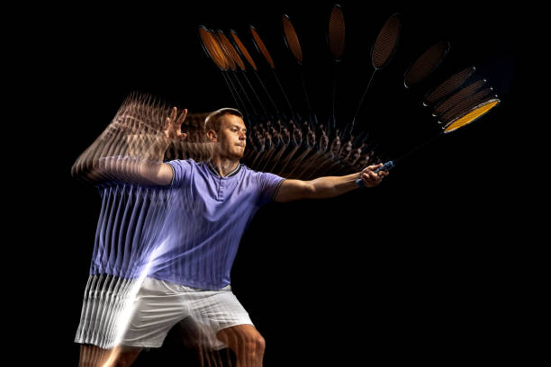 retrato de joven, jugador masculino de bádminton, lanzadera en movimiento y acción sobre fondo oscuro. efecto estroboscopio. - stroboscopic image fotografías e imágenes de stock