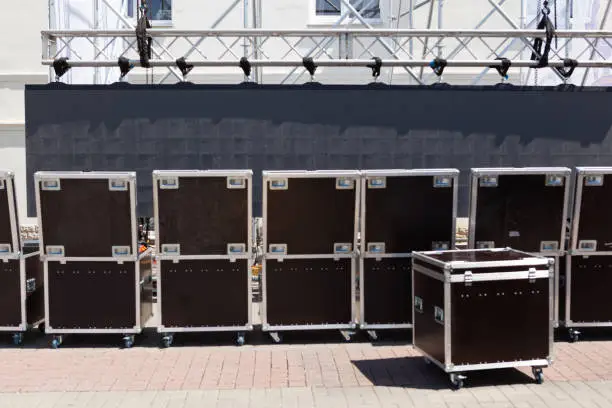 Photo of Concert or musical equipment in metal boxes. Preparing for a mass event on a city street. Transportation of sound equipment. Organization of events