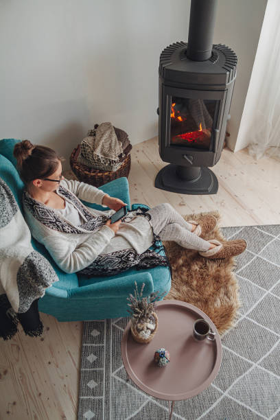 istock woman sitting in a cozy armchair, with a warm blanket, using a m 1328339526