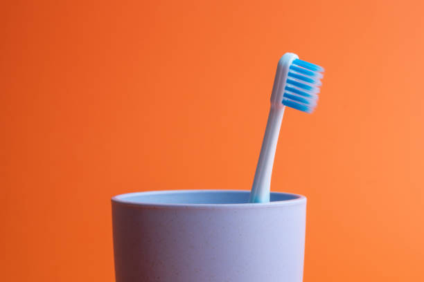 istock Toothbrushes in plastic cups on orange background 1328341659