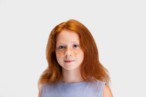 Beautiful cute little red-headed girl in casual outfit posing isolated on white studio background. Happy childhood concept. Sunny child. Happy childhood, education, emotions, facial expression concept