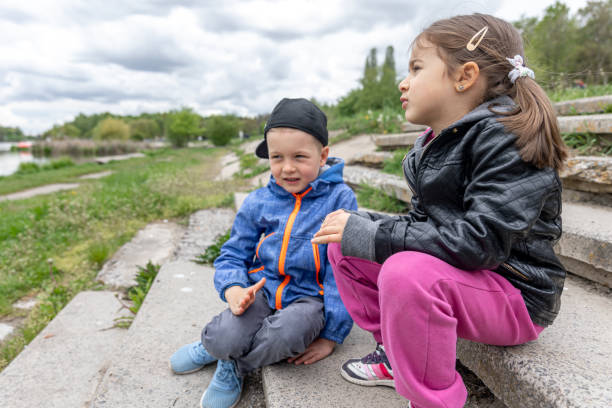 istock Little girl and boy communicate while sitting in the park. 1328345936