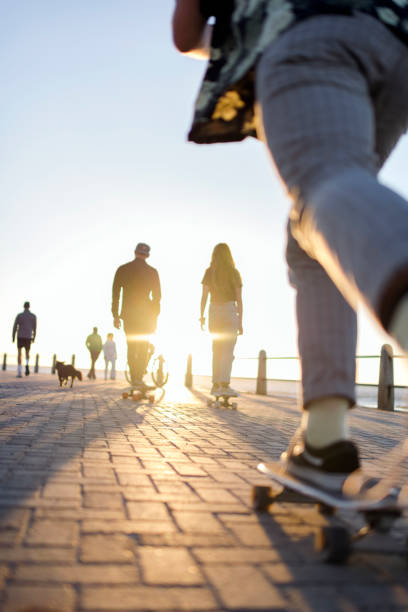 istock Low angle skateboarder following friends on promenade 1328346006