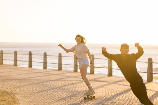 istock Two friends skateboarding along beachfront boardwalk 1328346045
