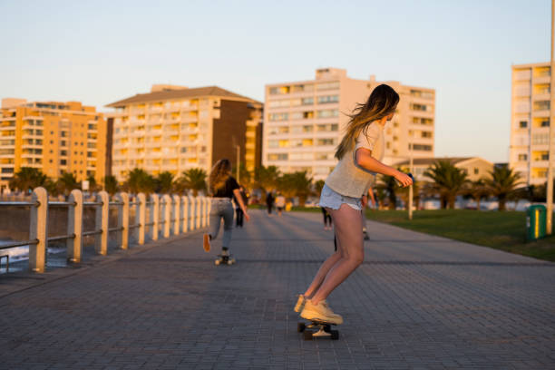 istock Young female skateboarders riding down promenade 1328346069