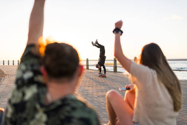 istock Friends cheer with arms raised as man does handstand on skateboard 1328346098