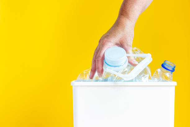 istock Woman's hand squeezing empty bottles and other plastic waste in a trash bin 1328346293