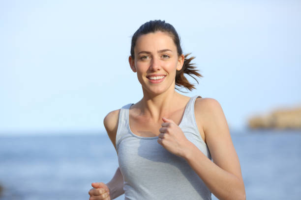 istock Happy runner running towards camera on the beach 1328346887