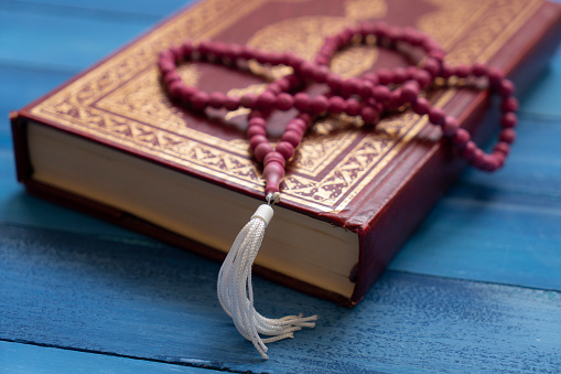 Holy Al Quran and prayer beads on wooden table. Ramadan muslim religion concept.