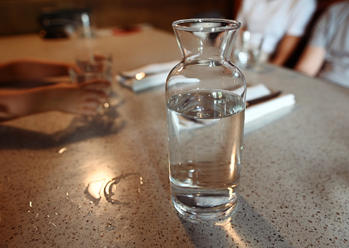 Transparent glass carafe or jug with water on a table