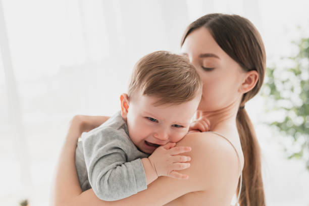istock Young single mother lulling cradling her crying little small son daughter toddler infant newborn baby. Colics, teething health problems. Postnatal depression. Motherhood and childcare 1328347607