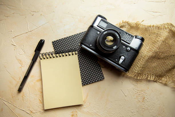 istock flat lay with spiral notepad, keyboard, pen and old camera on textured beige background. space for text 1328347634