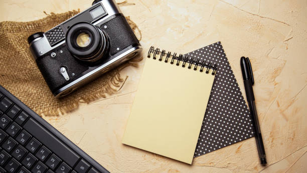 istock flat lay with spiral notepad, keyboard, pen and old camera on textured beige background. space for text 1328348243