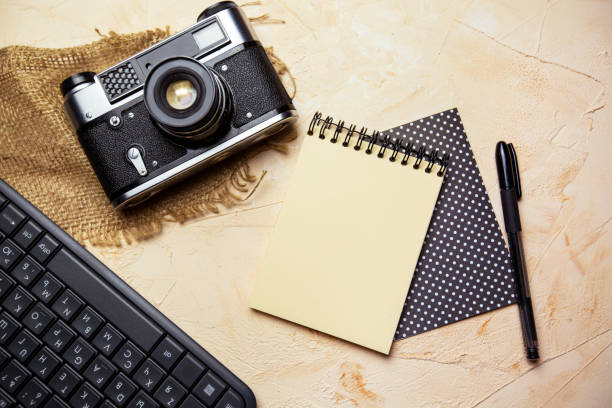 istock flat lay with spiral notepad, keyboard, pen and old camera on textured beige background. space for text 1328348272