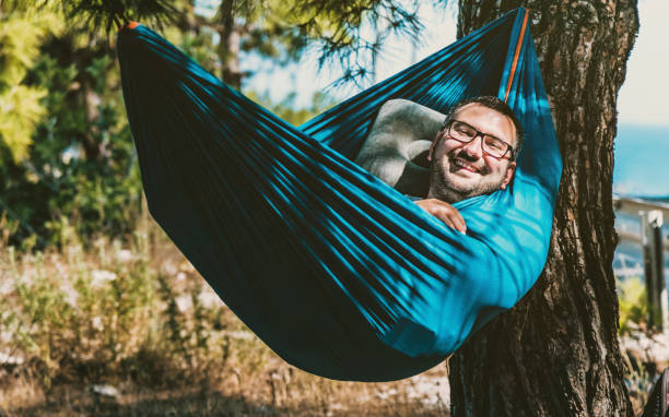 istock Young positive emotion with glasses laughing in hammock 1328348691