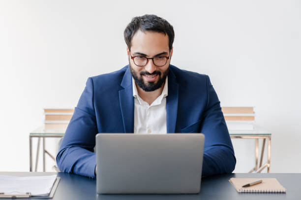 istock Front view of confident mature businessman tutor freelancer watching webinars, having online conversation, e-learning remotely on quarantine. Successful young manager working in home office 1328349216