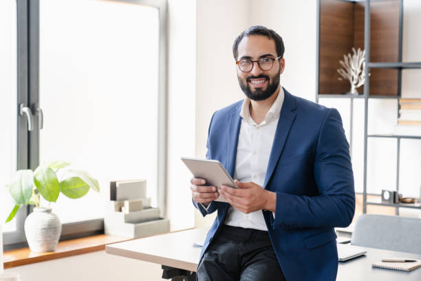 istock Smiling trustful islamic businessman tutor teacher using digital tablet for remote work, e-learning, online shopping, booking tickets, checking e-mails social media, loading contracts. 1328349985