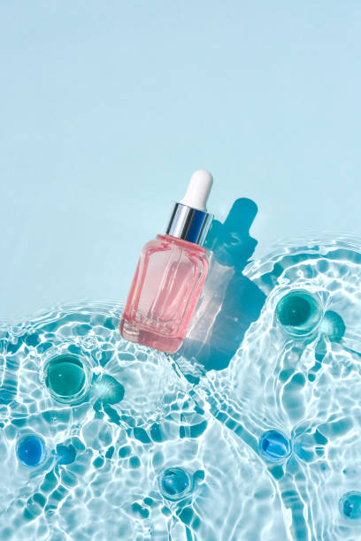 istock Mockup cosmetic pink bottle with pipette, water surface with waves Moisturizing advertising concept 1328350616