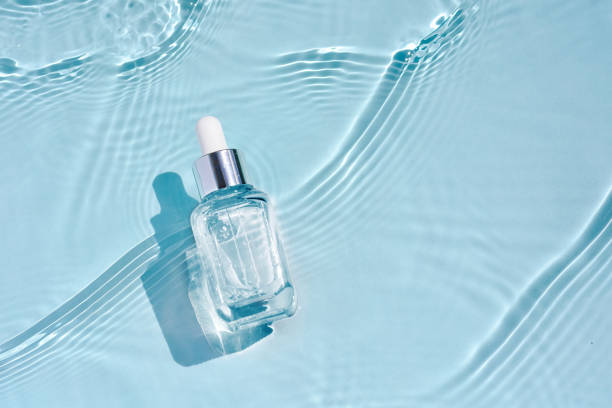 Cosmetic spa medical skincare, glass serum bottle with collagen on blue water background with waves. Advertising of medical product for anti-aging care, moisturizing and cleansing. Cosmetic spa medical skin care, glass serum bottle, micellar tonic with collagen on blue water background with waves. Advertising medical serum for anti-aging care, moisturizing and cleansing glass medicine blue bottle stock pictures, royalty-free photos & images