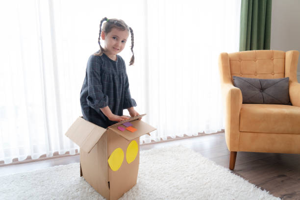 istock Little girl having fun with cardboard box 1328351360