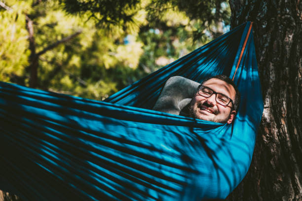 istock Young positive emotion with glasses laughing in hammock 1328351489