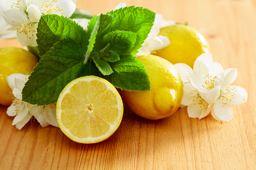 Flowering jasmine, mint, and lemons on a wooden background. Ingredients for making herbal tea.