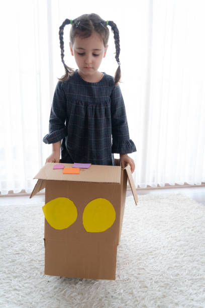 istock Little girl having fun with cardboard box 1328351875