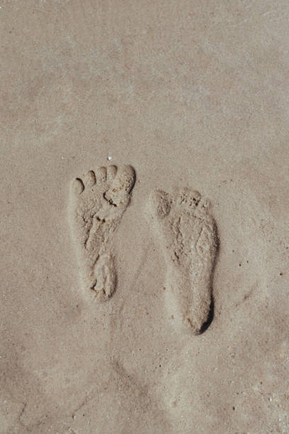 istock Two Footprints in sand at the Beach 1328351887
