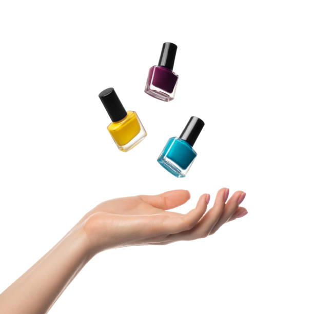 Nail polish bottles levitate, flying over a woman's hand stock photo