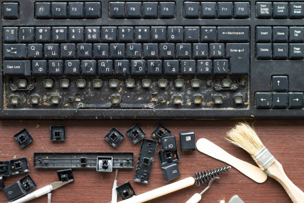 istock Old dirty computer keyboard with removed keys. The tools for repair and cleaning on the table in the workshop workspace. Close up 1328356178