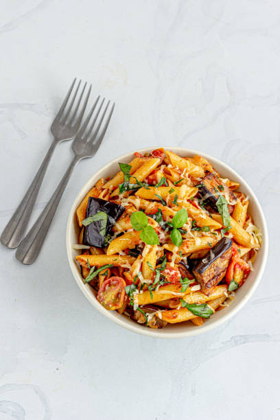 Italian Pasta and Eggplant Dish in a Bowl Directly Above Vertical Photo Pasta Alla Norma, Sicilian Pasta Dish with Eggplant Garnished with Basil Leaves tomato rigatoni stock pictures, royalty-free photos & images