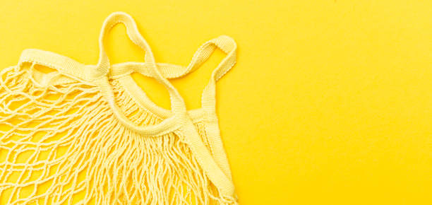 istock Empty mesh bag for shopping on a yellow background isolated. Zero waste shopping concept 1328358994