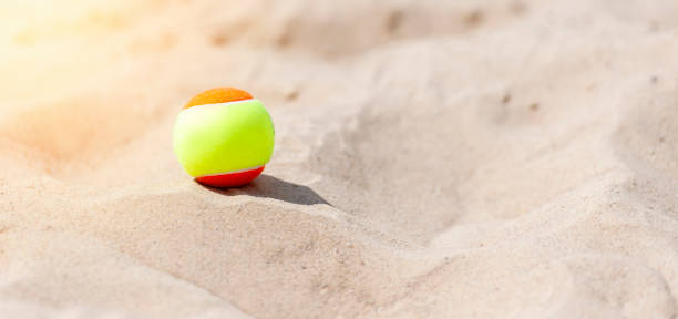 pelota de tenis en la arena en la playa de cerca. concepto de deporte profesional - tennis court tennis ball racket fotografías e imágenes de stock