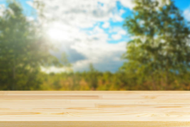 istock wood table top against blurred sky and trees background 1328359170